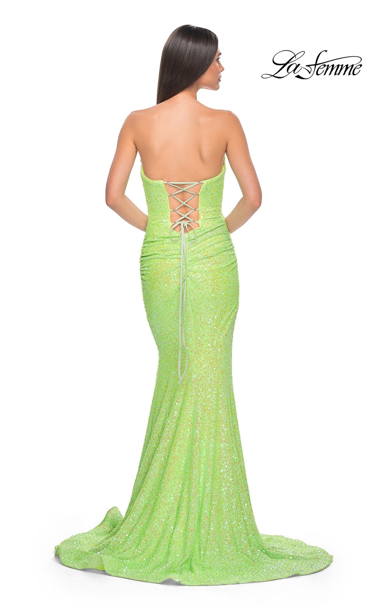 Woman in a strapless La Femme Long Sequin Prom Dress 39092 in neon green, featuring a lace-up back and floor-length design, stands facing away from the camera.